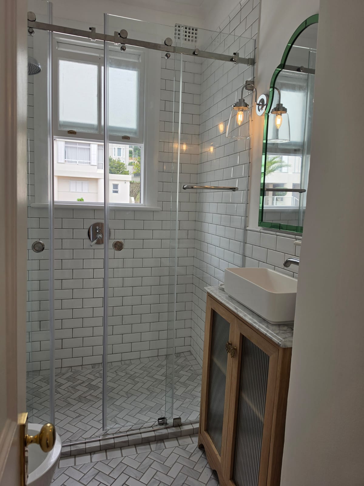 Walk-in shower with frameless sliding glass door, subway tiling and marble vanity