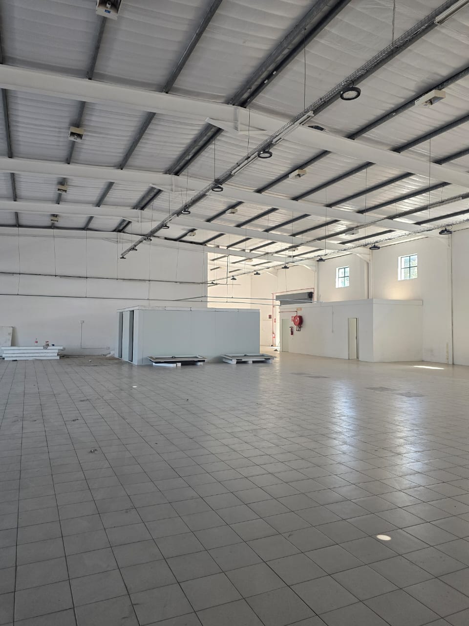 Empty warehouse unit before fit-out, with exposed steel roof structure and no ceiling