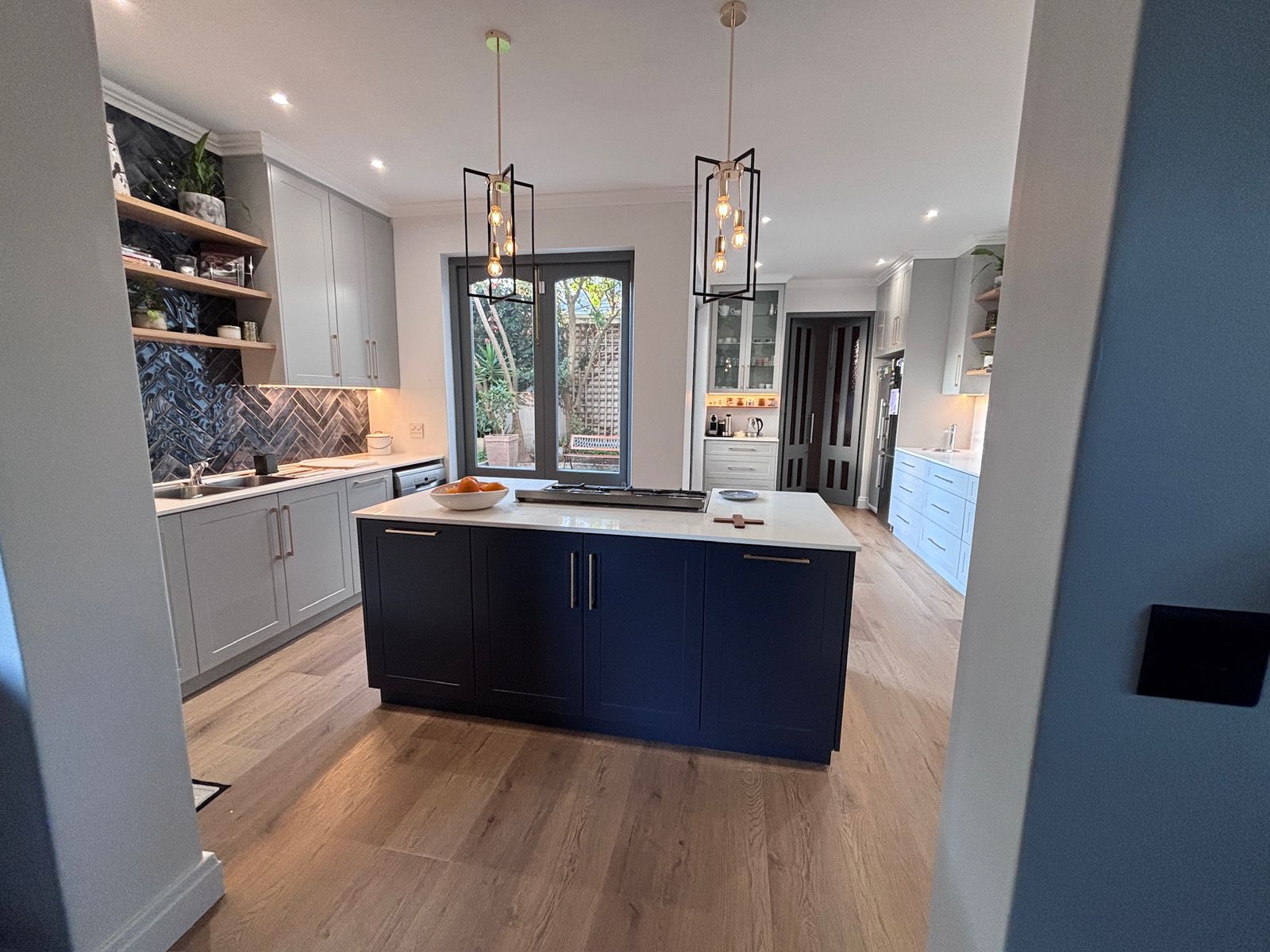 Open-plan kitchen with pendant lighting over the island and laminate flooring