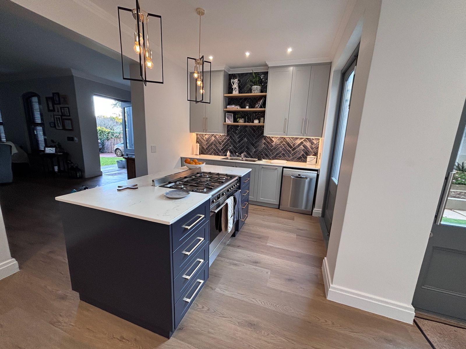 Kitchen with navy island, herringbone splashback and laminate flooring